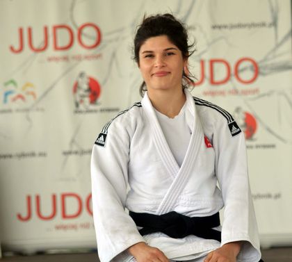 Kobieta w stroju judoki. W tle tablica z napisem Judo
