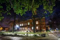 Nocne zdjęcie zabytkowego, ceglanego budynku dawnej wieży ciśnień otoczonej parkiem