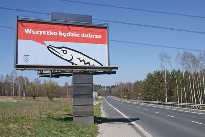 Bilbord cov1 1 Bilbord na tle błękitnego nieba. Obok droga.