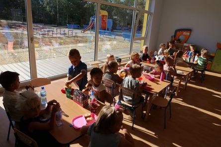 Grupa dzieci przedszkolnych bawiących się przy stolikach