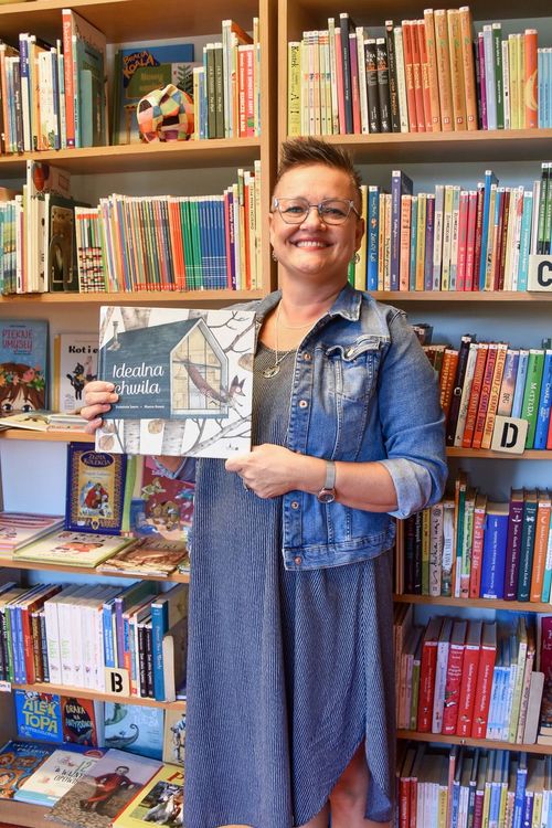 Bibliotekarka na tle regałów z książkami