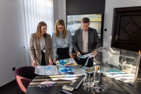 Zdjęcie przedstawia ludzi przeglądających laurki zrobione przez dzieci