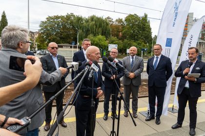 Zdjęcie przedstawia grupę mężczyzn stojących przy mikrofonach na peronie pkp. 