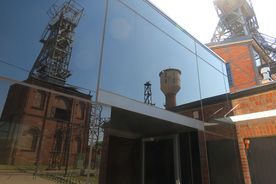 Zabudowania zabytkowej kopalni odbijające się w lustrzanych drzwiach