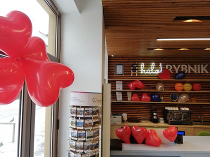 Wnętrze punktu informacji miejskiej. Półki z książkami i gadżetami, baloniki i kolorowe dekoracje.