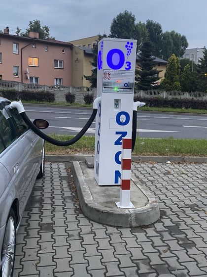 Urządzenie do ozonowania samochodu w trakcie pracy. W tle ulica, dom i zachmurzone niebo.