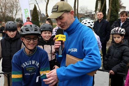 Dzieci zebrane wokół mężczyzny z mikrofonem w ręku