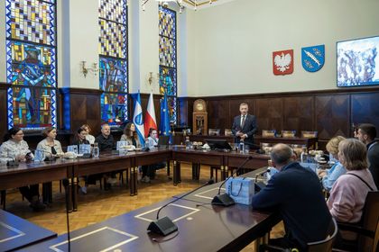 Grupa osób na sali sesyjnej podczas oficjalnego spotkania. 