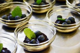 Szklane miseczki z owocami - borówki z listkiem mięty. 