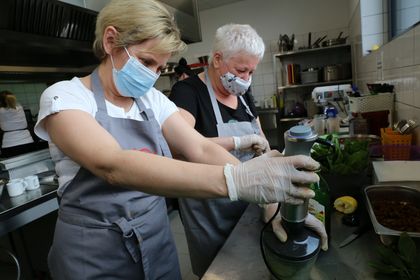 Dwie kobiety pracują przy przygotowywaniu posiłków w kuchni