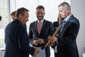 Dwóch mężczyzn wręcza nagrody mężczyźnie. 