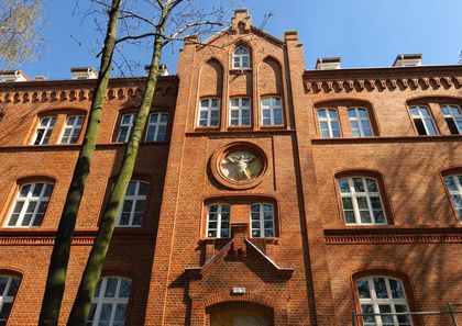 Oświetlona słońcem fasada wyremontowanego neogotyckiego, ceglanego budynku