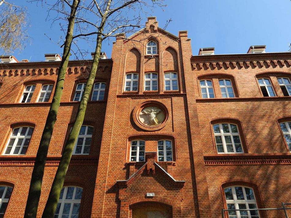 Oświetlona słońcem fasada wyremontowanego neogotyckiego, ceglanego budynku