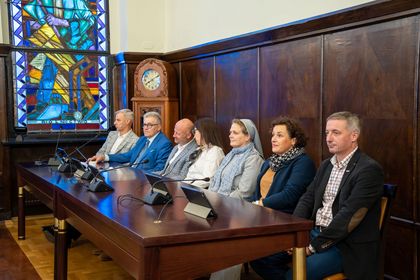 Grupa osób siedząca na sali sesyjnej. 