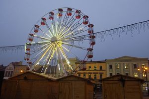 Podświetlona karuzela typu diabelski młyn, stojąca o zmierzchu na rynku miejskim. 