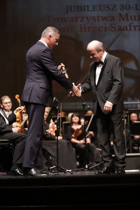 Mężczyźni stojący na scenie podczas wręczania nagród. 