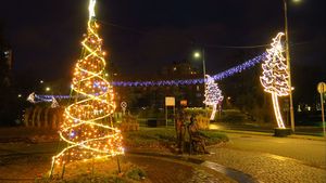 Wieczór. Świątecznie udekorowane miasto - lampki nad ulicami, choinki, i inne ozdoby.