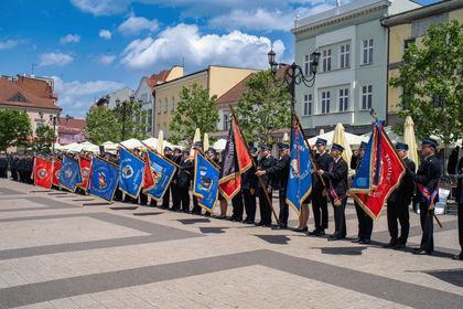 Zdjęcie przedstawia ludzi w mundurach strażackich trzymających sztandary.
