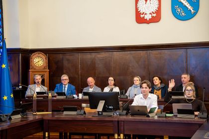 Grupa osób siedząca na sali sesyjnej. 