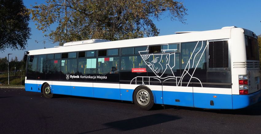 Biało-niebieski autobus komunikacji miejskiej, stojący na pustym placu