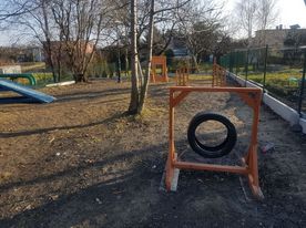 Wybieg boczna fot.RSK 4 Ogrodzony plac centralnie drzewo, na pierwszym planie element placu zabaw dla psów