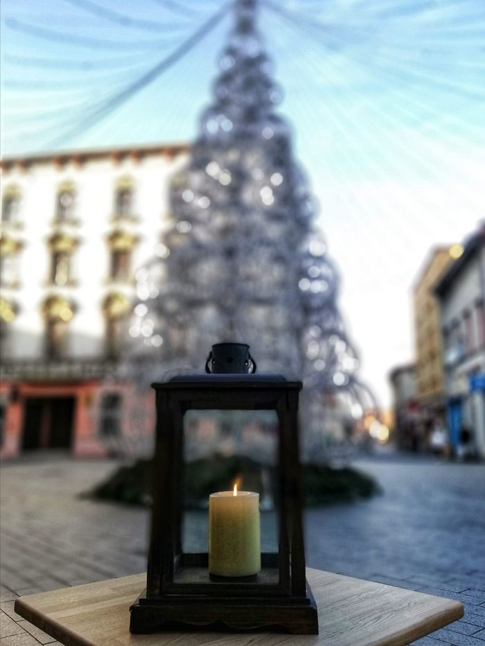 Lampion na tle ledowej choinki. Wokół kamienice.