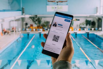 Smartfon z wyświatlającą się kartą Rybka na tle basenu 