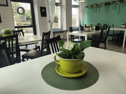 Zdjęcie przedstawia wnętrze restauracji. Widać stoliki, krzesła.