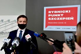Prezydent Rybnika na tle tablicy z napisem Rybnicki Punkt Szczepień. Przed nim mikrofony mediów