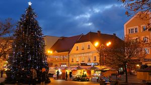 Wieczór. Świątecznie udekorowane miasto - lampki nad ulicami, choinki, i inne ozdoby.