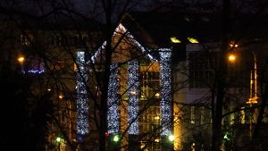 Wieczór. Świątecznie udekorowane miasto - lampki nad ulicami, choinki, i inne ozdoby.