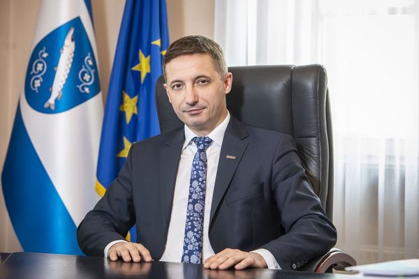 Prezydent Rybnika Piotr Kuczera przy biurku, w tle flaga Rybnika i UE
