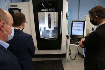 Trzech mężczyzn oglądających sprzęty elektroniczne w nowocześnie wyposażonej pracowni kształcenia zawodowego 