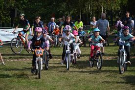 Grupa dzieci na rowerach podczas zawodów MTB w lesie. 