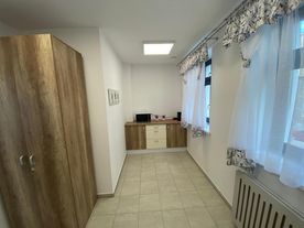 Przedpokój, jasne wnętrza, ciemna szafa i komoda, kaloryfer, okna. 