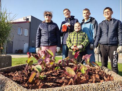 Grupa uczniów sadzi kwiaty z pracownikami Zarządu Zieleni Miejskiej 