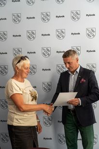 Zdjęcie przedstawia mężczyznę, który wręcza dyplom kobiecie.