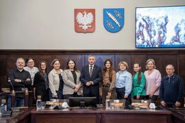 Grupa osób pozujących do zdjęcia na sali sesyjnej. 