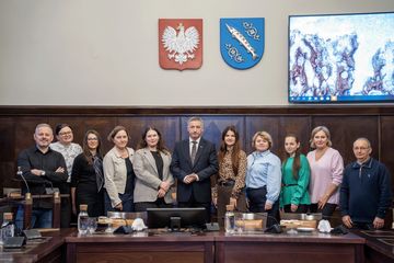 Grupa osób pozujących do zdjęcia na sali sesyjnej. 