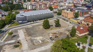 Pusty plac budowy pomiędzy zabudową śródmiejską i parkingiem wielopoziomowym. Widok z lotu ptaka.