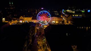 Miasto nocą z lotu ptaka. Na pierwszym planie oświetlony diabelski młyn