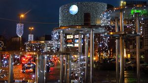 Wieczór. Świątecznie udekorowane miasto - lampki nad ulicami, choinki, i inne ozdoby.