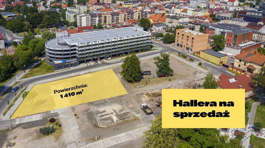 Pusty plac budowy pomiędzy zabudową śródmiejską i parkingiem wielopoziomowym. Fragment terenu zaznaczony na żółto. Widok z lotu ptaka.