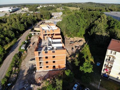 Budynki wielorodzinne w trakcie budowy. W tle istniejąca zabudowa i zieleń.
