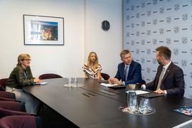 Zdjęcie przedstawia dwie kobiety i dwóch mężczyzn siedzących przy biurku.