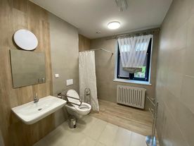 Łazienka ze zlewem, toaleta i prysznicem, wszystko w jasnych, stonowanych kolorach.