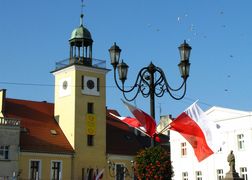 Ratusz miejski na tle błękitnego nieba. Na pierwszym planie polska flaga . 