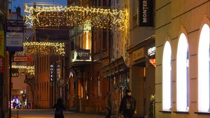 Wieczór. Świątecznie udekorowane miasto - lampki nad ulicami, choinki, i inne ozdoby.