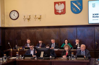 Grupa ludzi siedzących na spotkaniu w urzędzie miasta.