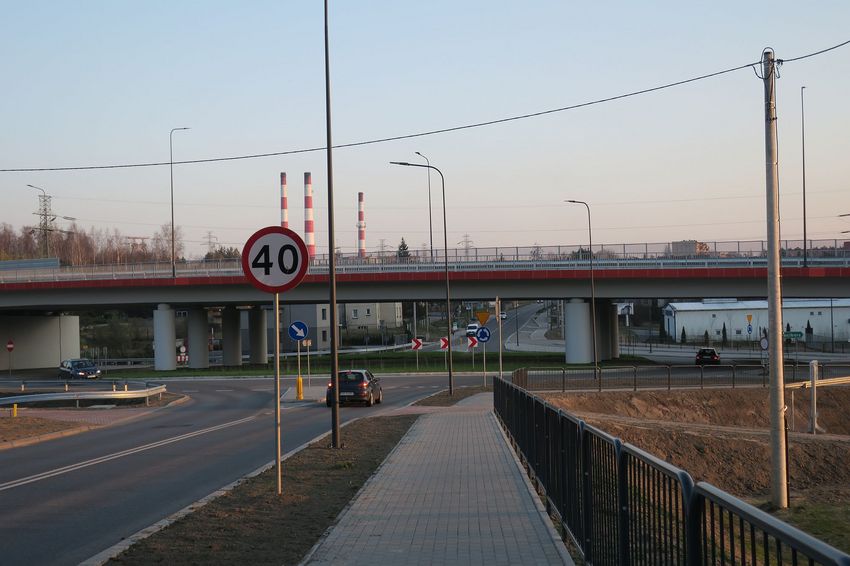 Ulica, nad któą przebiega wiadukt drogowy. W tle trzy kominy kopalni
